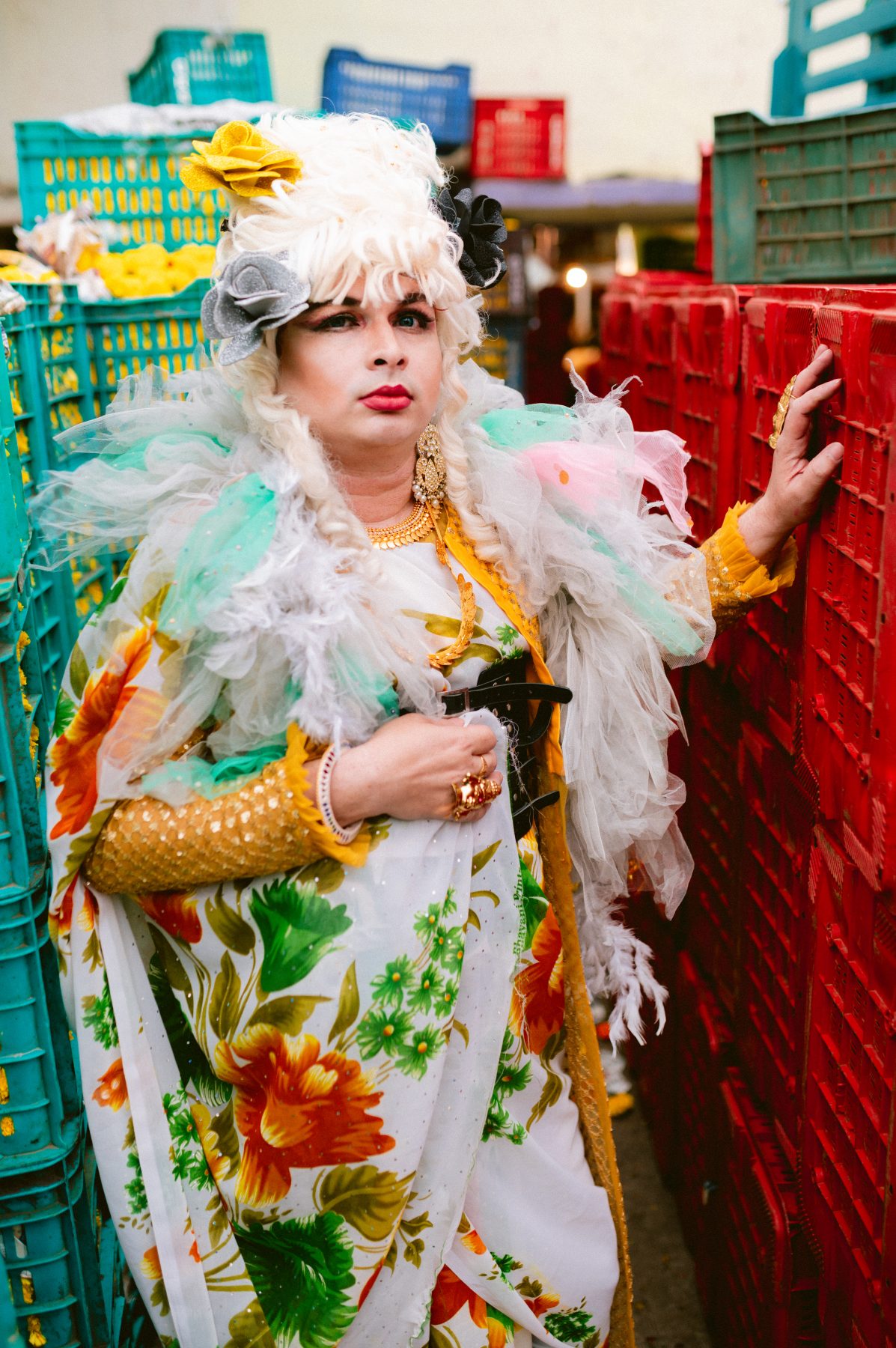 Patruni in stunning drag, surrounded by buckets full of flowers.