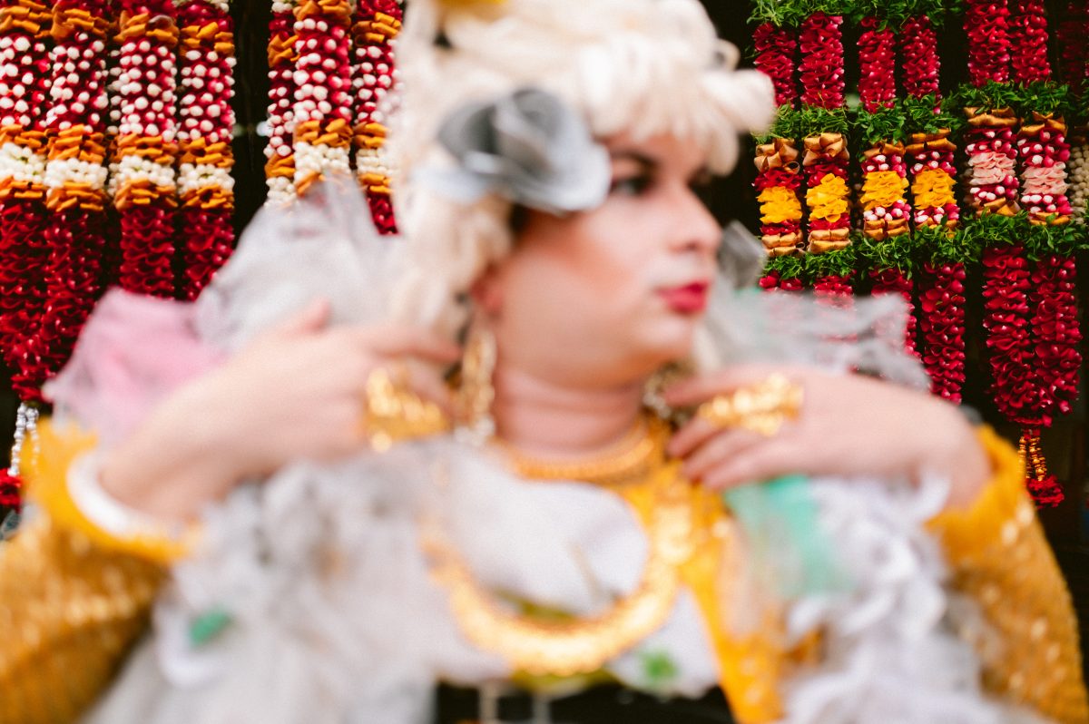 Patruni in the foreground, with the camera lens focused on the flower garlands behind them.