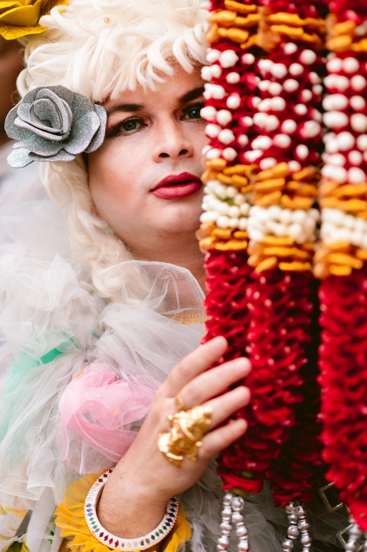 Patruni peeks out from behind rows of flower garlands.