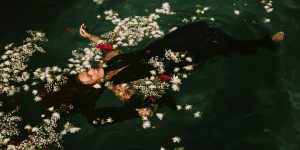 A woman floating in flowers in the water, reminiscent of Ophelia from Shakespeare's Hamlet.