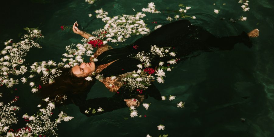 A woman floating in flowers in the water, reminiscent of Ophelia from Shakespeare's Hamlet.