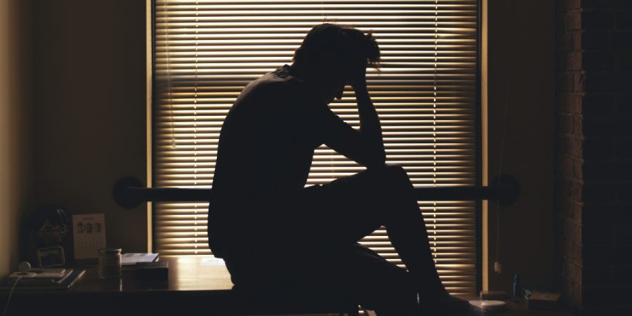 Silhouette of a man in front of window shutters.